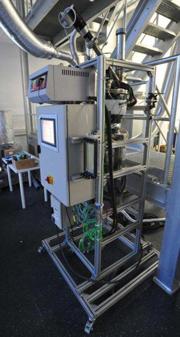 Auf dem Bild befindet sich ein Anlageaufbau mit einem Wirbelschichtreaktor im Labormaßstab zur Untersuchung von Agglomerationsvorgängen.
