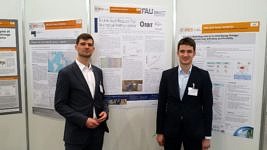 Die Kollegen Trabold und Weidlich vor der Posterwand an der IRES 2019 in Düsseldorf
